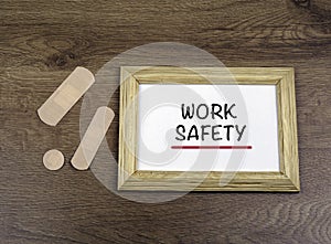 Medical plasters and wooden frame with text: Ã¢â¬ÅWork SafetyÃ¢â¬Â o photo